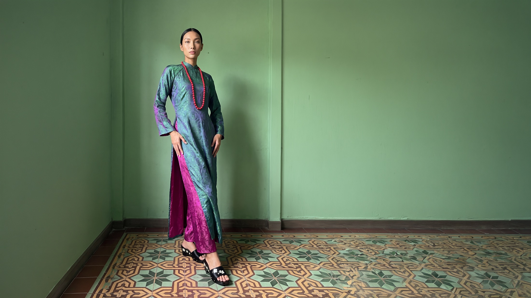 A model wearing the Bích Cẩm Áo Dài Set in jade-green and plum Nha Xá silk
