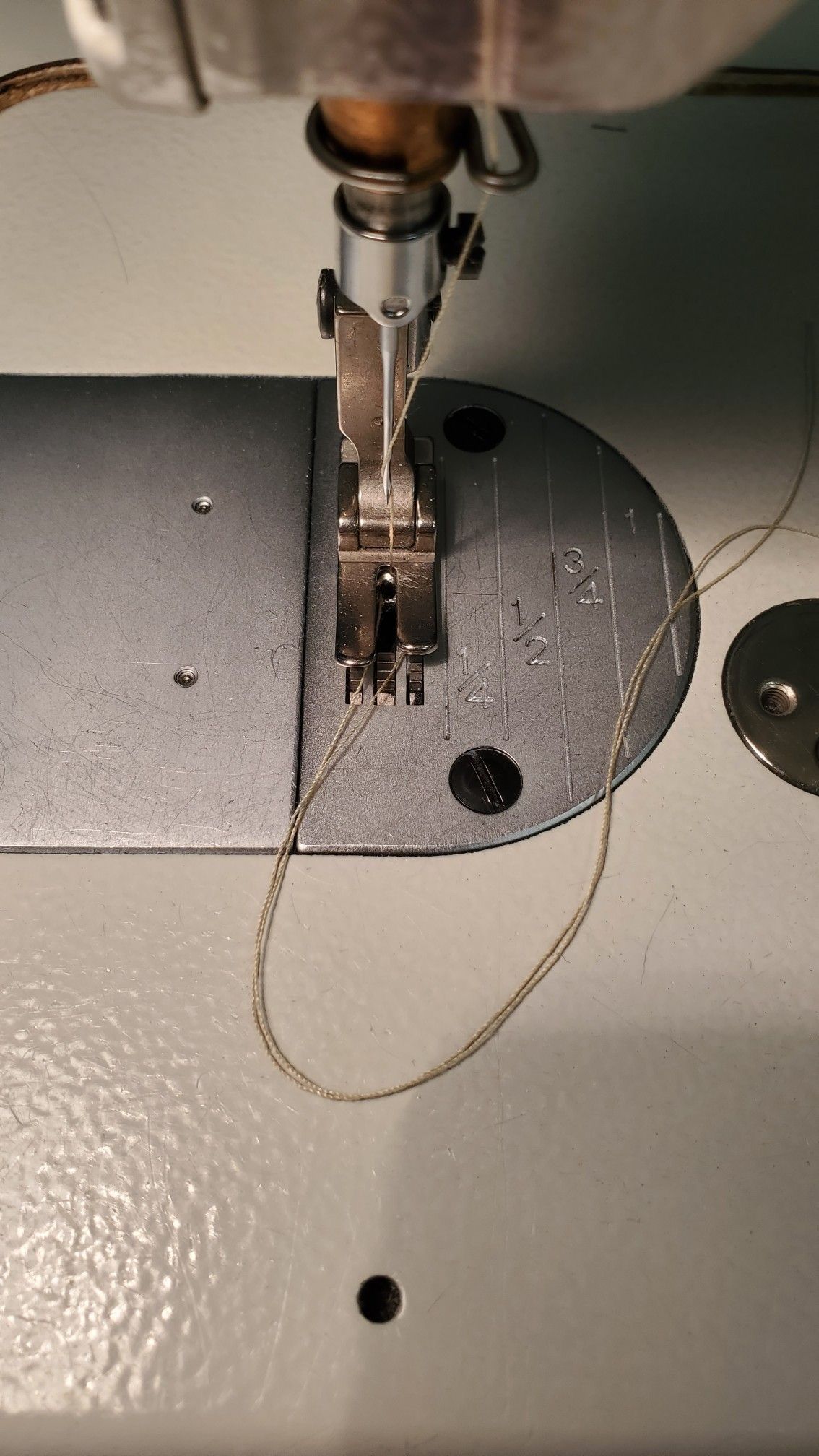 Close-up of a sewing machine needle threading fabric by hand